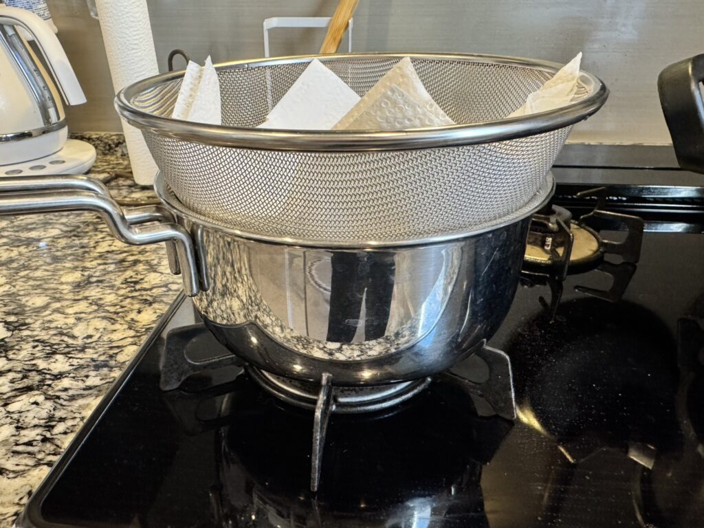 スープを濾すために鍋の上にザルを乗せてキッチンペーパーを置いている様子