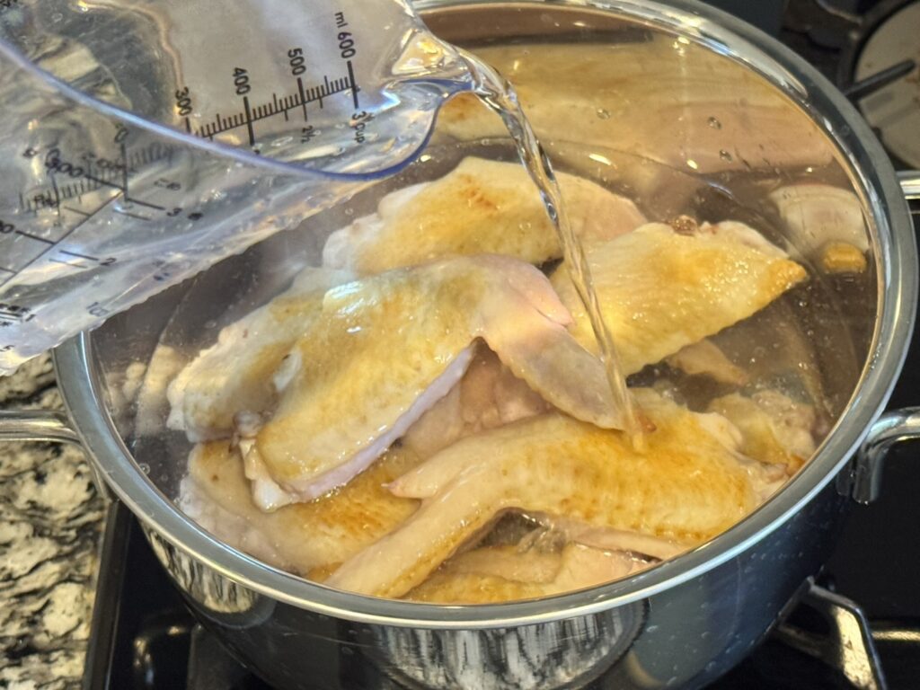 焼いた手羽先を鍋に入れている様子