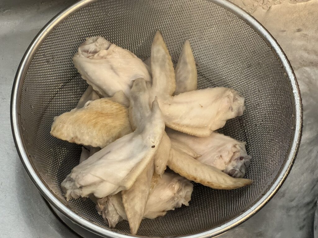 茹でた手羽先をザルにあげている様子