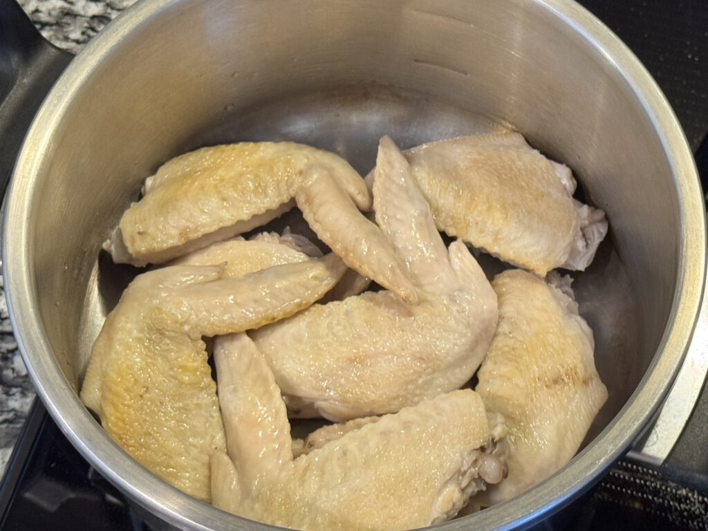 茹でた手羽先を圧力鍋に入れている様子