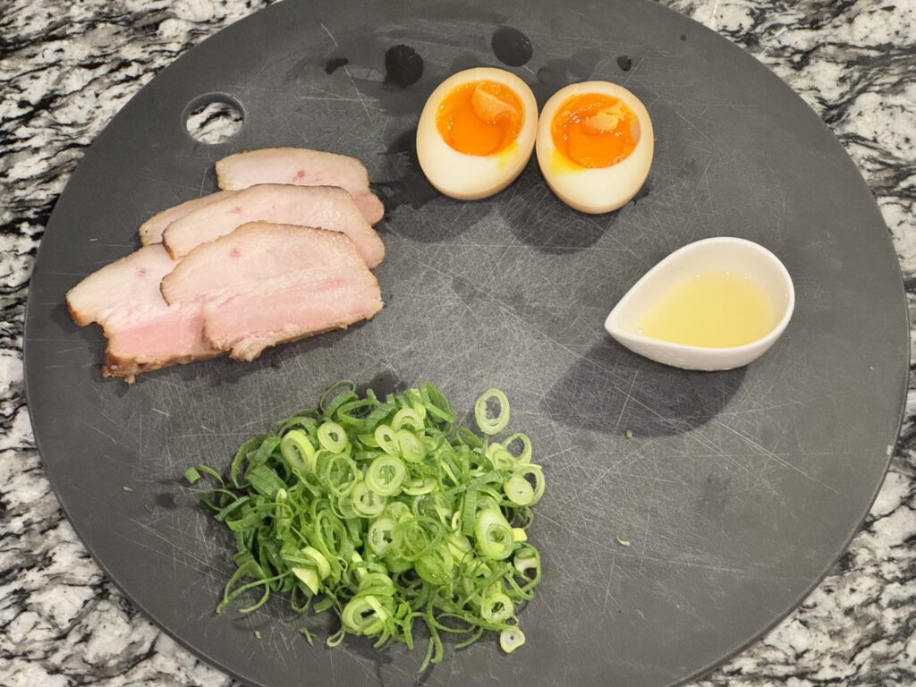 ラーメンのトッピング(ネギ、チャーシュー、味玉、鶏油)の写真