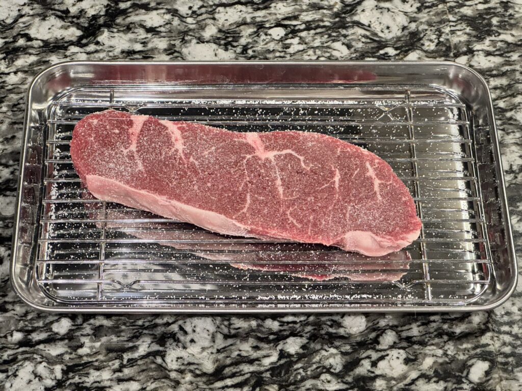 キッチンペーパーでドリップを拭いたオーケーストアで購入したグラム369円のオージービーフに塩を振っている状態