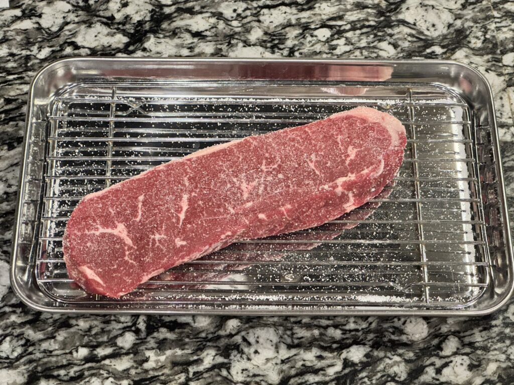 キッチンペーパーでドリップを拭いたオーケーストアで購入したグラム369円のオージービーフに塩を振っている状態