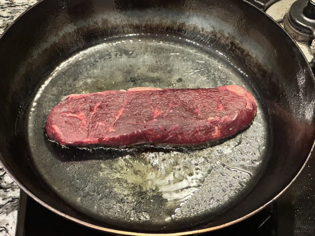 オーケーストアのオリーブオイルを入れた山田鉱業所の厚さ2.3mmの鉄フライパンにルビー色のオージービーフを入れたところ