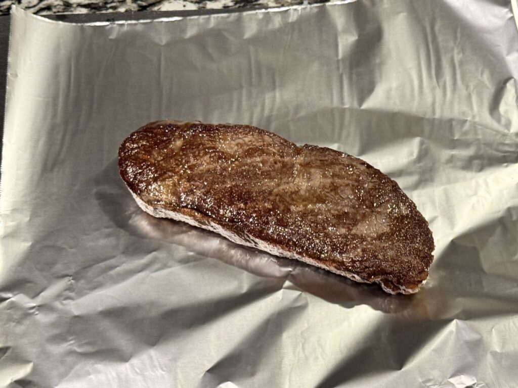 焼き上がってアルミホイルに置かれているステーキ
