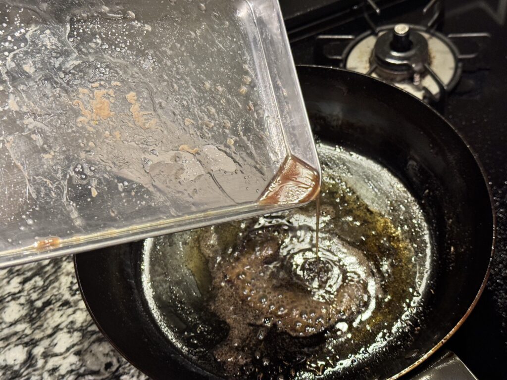 山田工業所の鉄フライパンに溶かしたバターと乾燥タイムとレモン果汁に豚肉の肉汁を加える様子