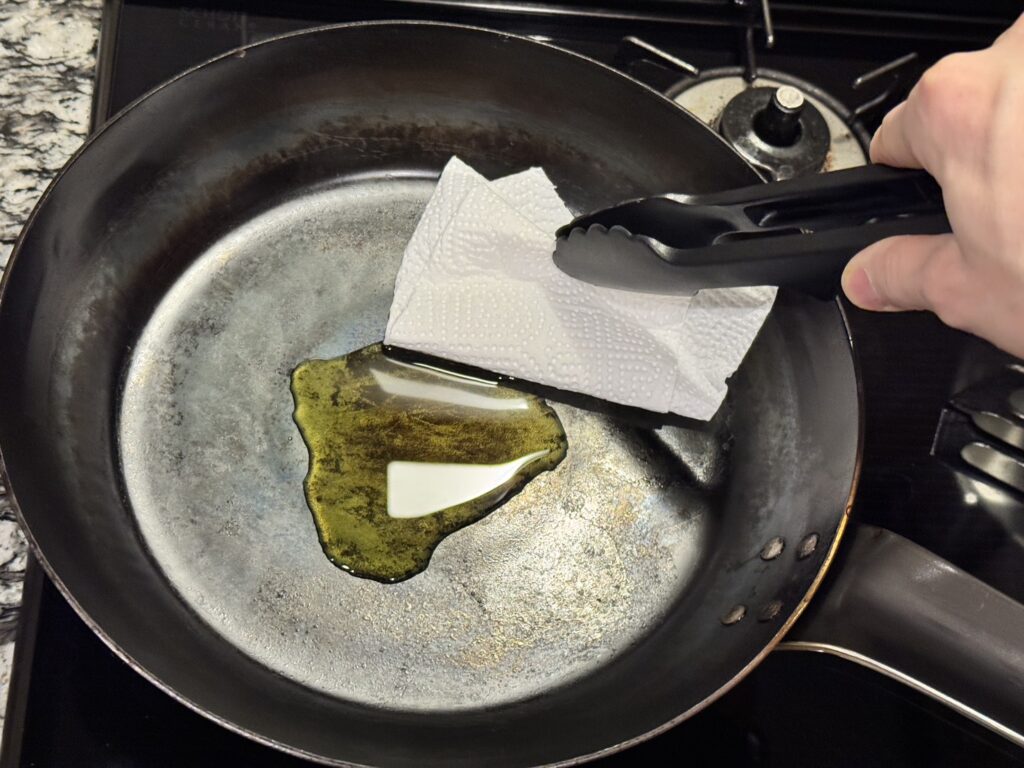 山田工業所の鉄フライパンに乗ったオリーブオイルをキッチンペーパーで拭っている様子