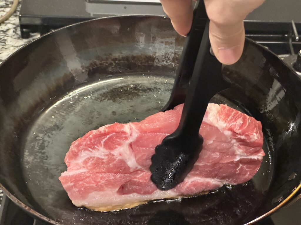 山田工業所の鉄フライパンで豚肉を立てて焼いている状況