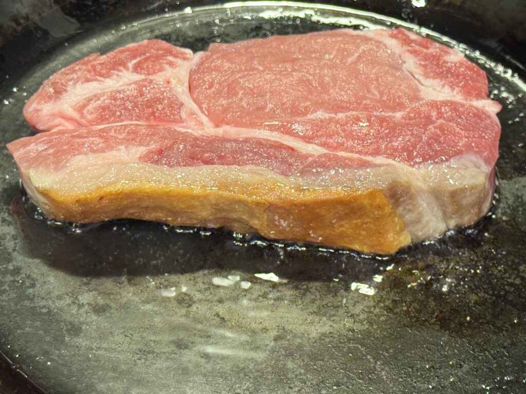 山田工業所の鉄フライパンで豚肉の脂身が焼けた豚肉を焼いている状態