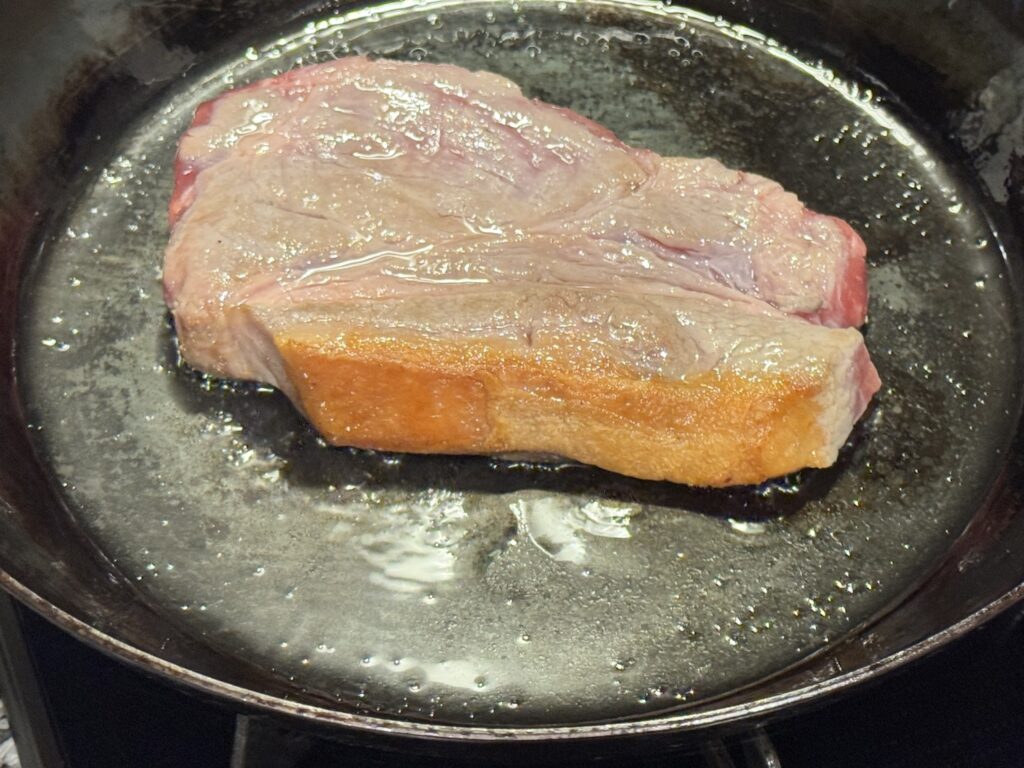 山田工業所の鉄フライパンで豚肉の脂身が焼けた豚肉を焼いている状態