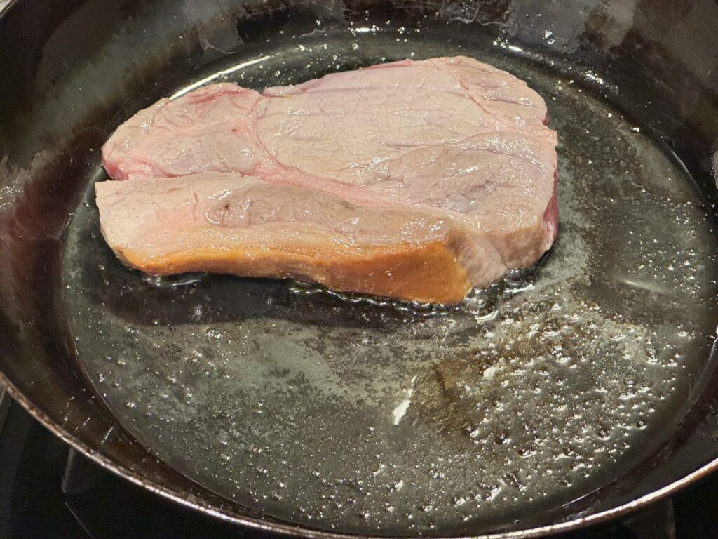 山田工業所の鉄フライパンで豚肉の脂身が焼けた豚肉を焼いている状態