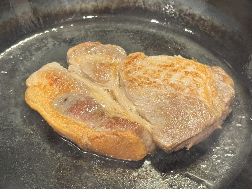 山田工業所の鉄フライパンでポークステーキを仕上げている様子