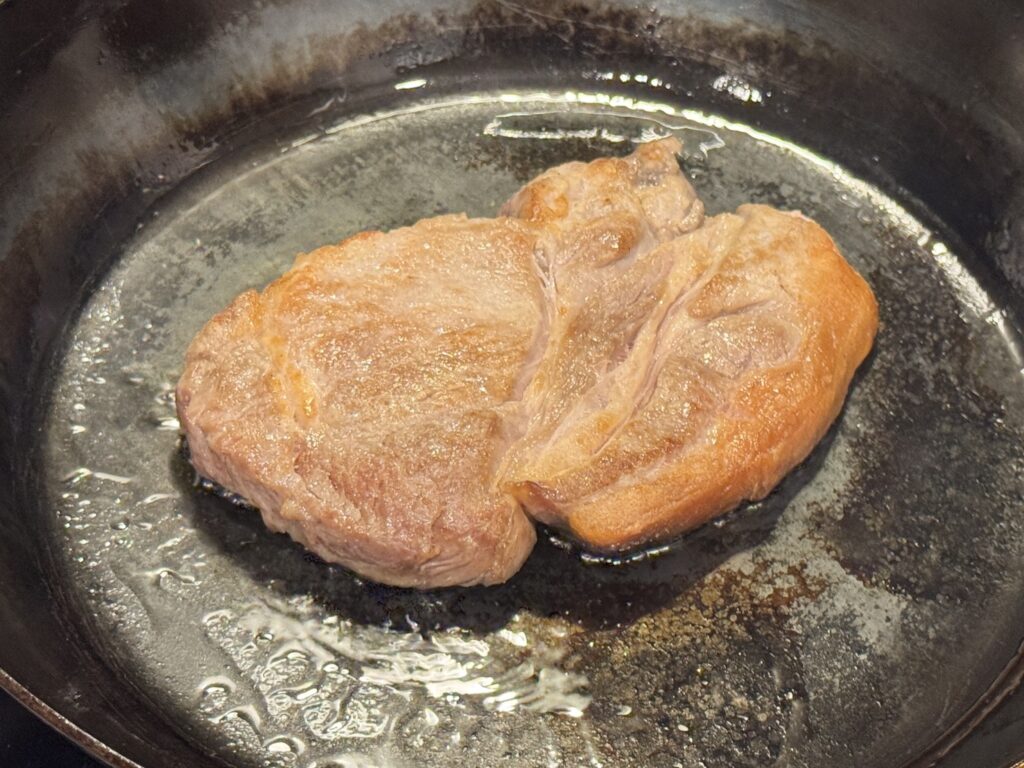 山田工業所の鉄フライパンでポークステーキを仕上げている様子