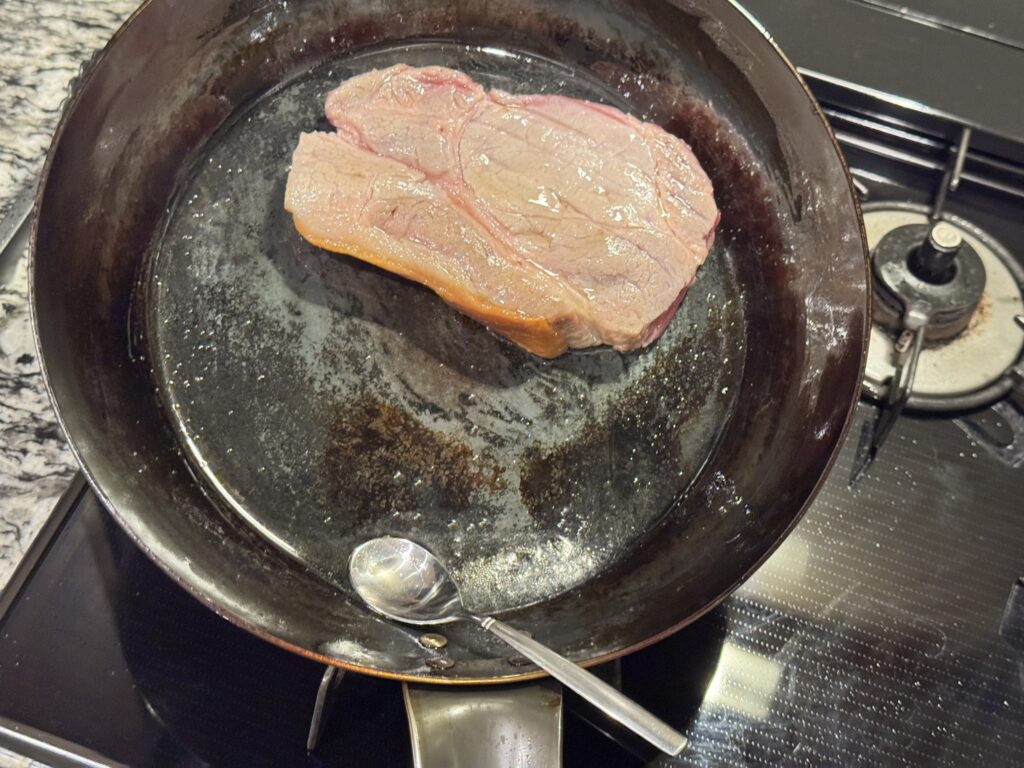 山田工業所の鉄フライパンで豚肉をアロゼしている様子