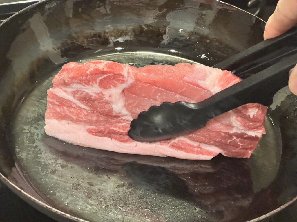 山田工業所の鉄フライパンで豚肉を立てて焼いている状況