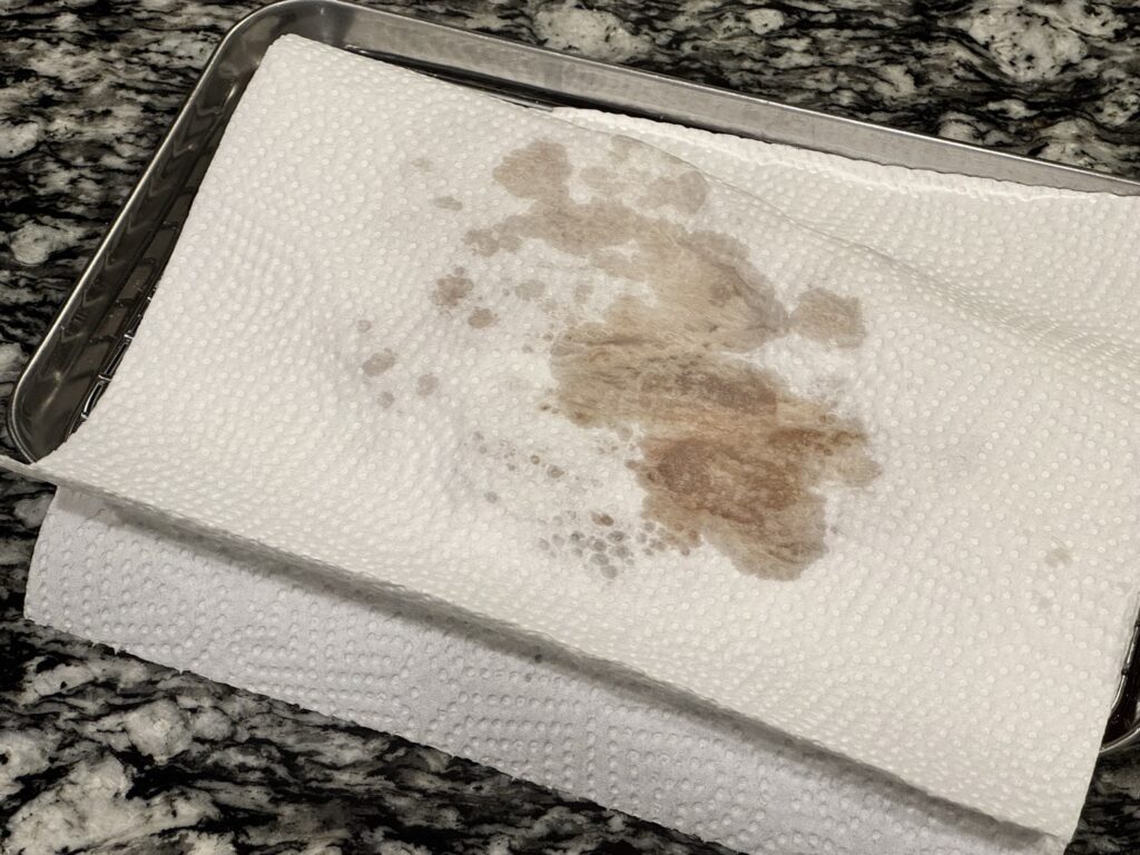 キッチンペーパーで表面の拭っている豚肉