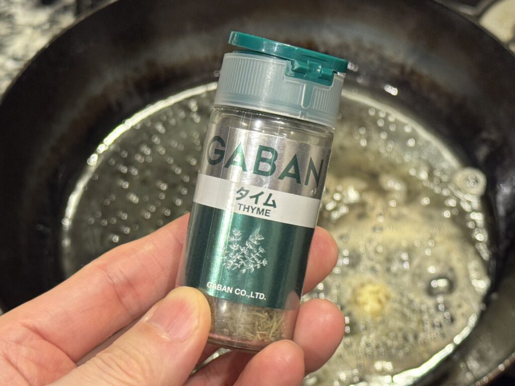 山田工業所の鉄フライパンに溶かしたバターに乾燥タイムを入れる様子